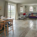 Large living and dining room with stone floor and modern fireplace.