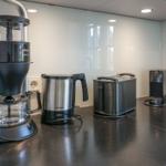 Kitchen counter with coffee maker, kettle, toaster, and coffee machine.