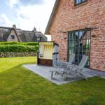 Red brick house with terrace, beach chair, and lounge chairs in the garden.
