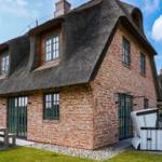 House with thatched roof and brick facade, garden area with table and seating.