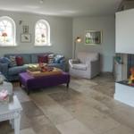 Living room with fireplace, sofa, armchair, and stone floor