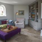Living room with sofa, armchair, fireplace, and bookcase.