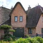 A two-story house with thatched roofs and red brick walls.