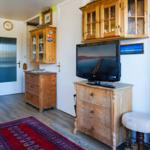 Wohnzimmer mit Holzmöbeln, Fernseher und Teppich