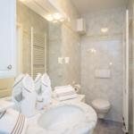 Badezimmer mit Marmor, Waschbecken, Toilette und Handtuchhalter.