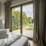 Schlafzimmer mit Blick auf Garten durch Glastür
