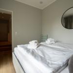 Schlafzimmer mit Bett, Handtüchern und runden Spiegel an der Wand.