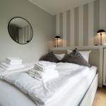 Schlafzimmer mit Bett, Handtüchern, Spiegel und Lampe an der Wand.
