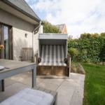 Terrasse mit Esstisch, Strandkorb und Grünfläche