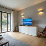 Wohnzimmer mit Fernseher, Sessel und Blick auf Garten