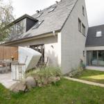 Moderne Villa mit Garten, Terrasse und weißen Rattanmöbeln.
