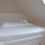 Bedroom with white bed and stacked towels under sloped ceiling