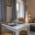 Esszimmer mit Tisch und Stühlen, Sofa und Fenstern mit Vorhängen.