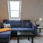 Ein Wohnzimmer mit blauem Sofa, zwei Dachfenstern und einem schwarzen Couchtisch.