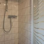 Duschkabine mit Marmorfliesen und gebogenem Glas