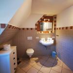 Badezimmer mit Dusche, Waschbecken und Toilette unter Dachschrägen.