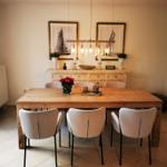 Holztisch mit Stühlen, Deckenleuchte und Wandbildern im Esszimmer.