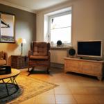 Wohnzimmer mit Sessel, Fernseher und Fenster
