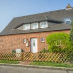 Red brick house with white windows and wooden fence.