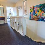 Hallway with wall painting, mirror, and staircase to upper floor.