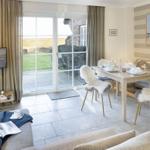 Living and dining area with TV, table, chairs, and view of garden.