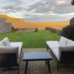 Terrace with two sofas and table. View of lawn and hills.