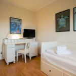Bedroom with bed, desk, and TV. Wall art features sea animals.