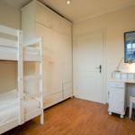 Room with bunk bed, wardrobe, desk, and wall art with sea animals.