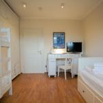 Room with bunk bed, single bed, desk, and TV.