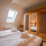 Bedroom with sloped ceiling, double bed, wooden wardrobe, and skylight.