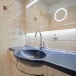 Bathroom with blue sink and illuminated mirror