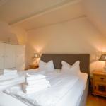 Bedroom with double bed, two nightstands, and wardrobe under sloped ceiling.