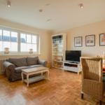 Living and dining area with sofa, TV, dining table, and bookshelf.