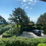 Thatched house with garden, car parked, sea view.