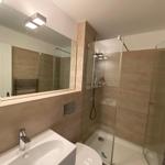Badezimmer mit Dusche, Waschbecken und Spiegel.