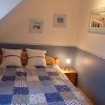 Bedroom with sloped ceiling, bed with pillows, and nightstand with lamp.