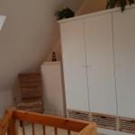 Bedroom with sloped ceiling, window, wardrobe, and chair.