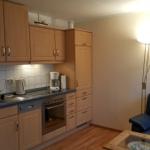 Kitchen with wooden cabinets and living area with sofa and floor lamp.