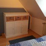 Bedroom with sloped ceiling, wardrobe, and bed.