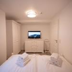 Schlafzimmer mit Bett, TV und Kleiderschrank.