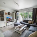 Wohnzimmer mit Sofa, Fernseher und Terrassentür.