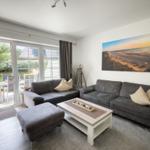 Wohnzimmer mit grauem Sofa, Couchtisch und Blick auf den Garten.