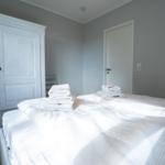 Bedroom with bed, white wardrobe, and folded towels.