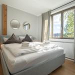 Bedroom with bed, two round mirrors, and window with view of trees.