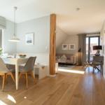 Dining area with table and chairs, living room with sofa and windows
