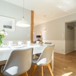 Dining area with white table, gray chairs, and floral arrangement.