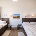 Room with two beds, wall lamps, and pictures on the walls.