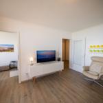 Living room with TV, armchair, and kitchen area.