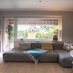 Wohnzimmer mit Sofa, Fenster und Blick auf grüne Umgebung.
