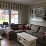 Ein Wohnzimmer mit grauem Sofa, weißem Tisch und Fenster zur Außenseite.